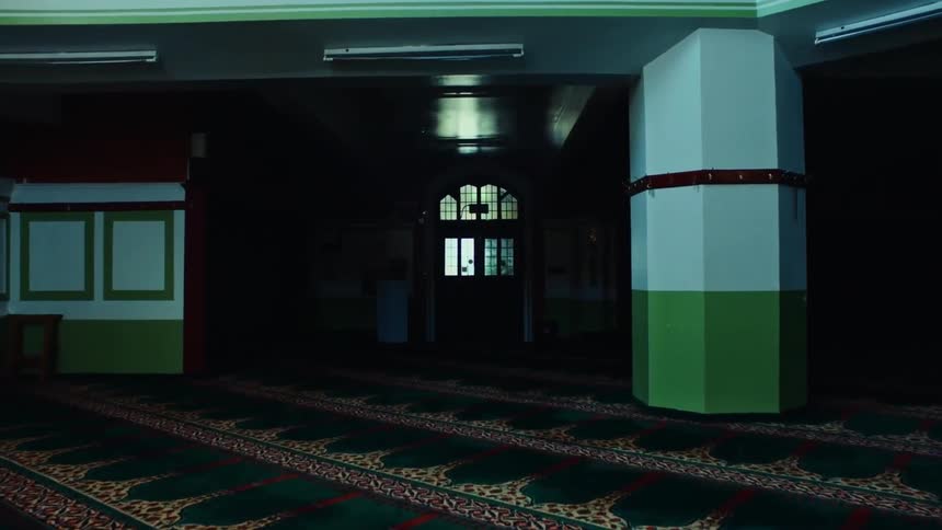 Internal architecture of a lobby with greenish carpet and a door in the background