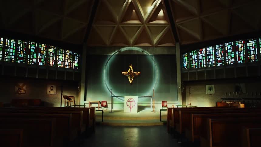 A cross floats over an altar at the front of a church