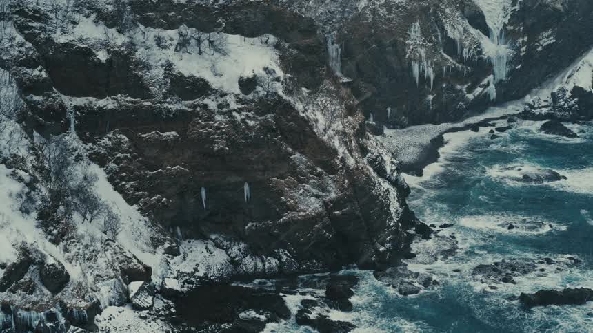 Waves crash against the mountain covered shore