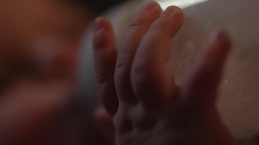 Hands of a baby holding her bottle while drinking milk