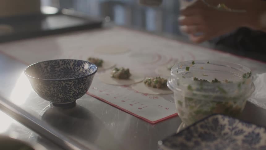 Womans hands putting ingredients into a small dough on a countertop