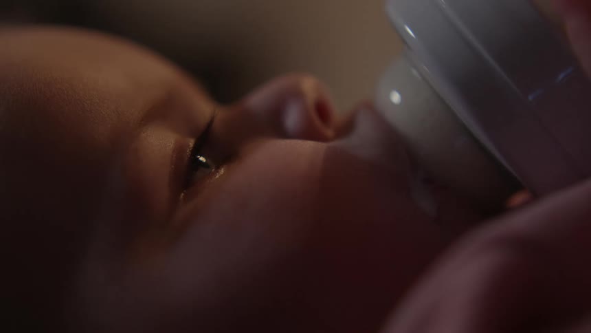 Side portrait of a baby breastfeeding from a bottle
