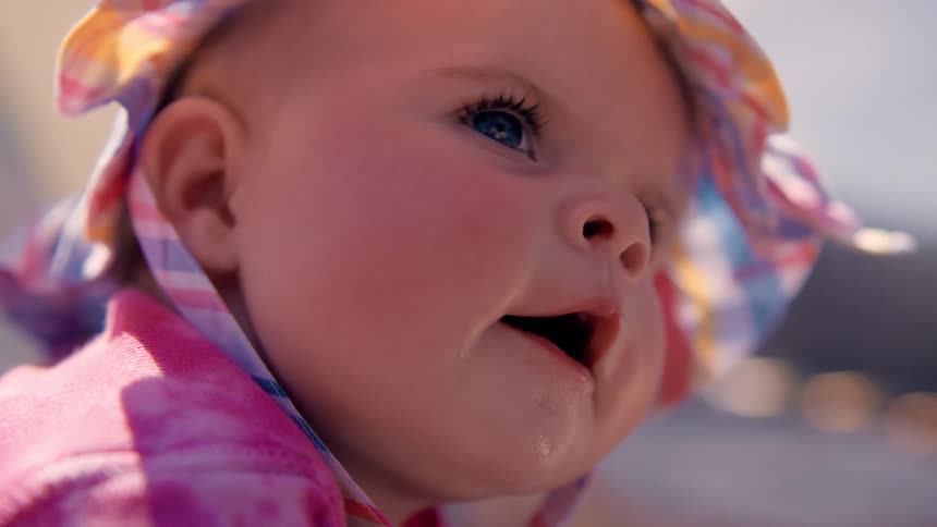 Portrait of a baby wearing a hat outdoors with a sun glare