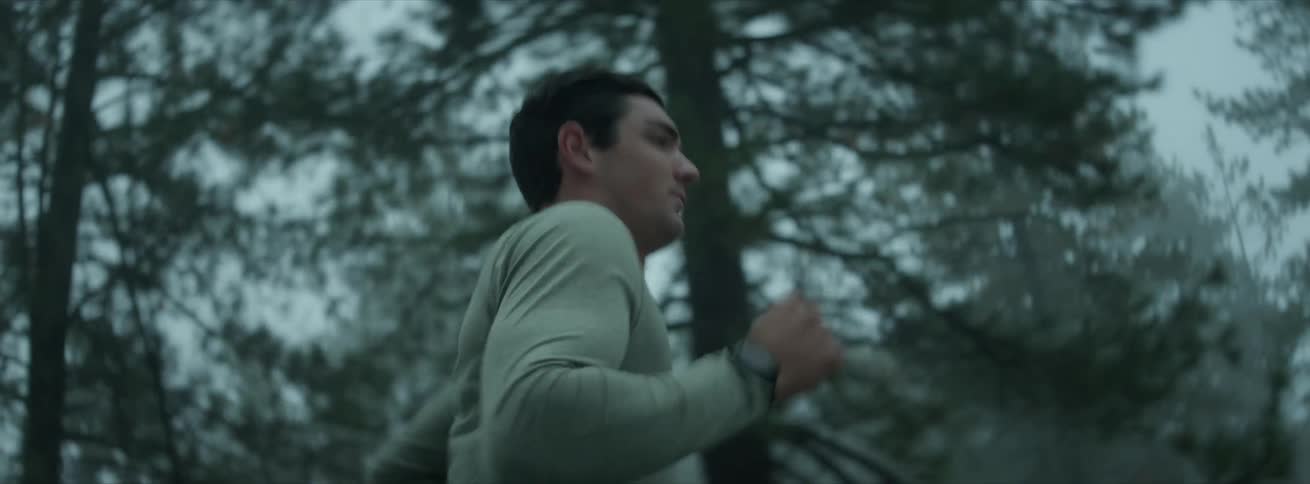 Concentrated and determined man running in a straight line next to trees on a foggy and cloudy day
