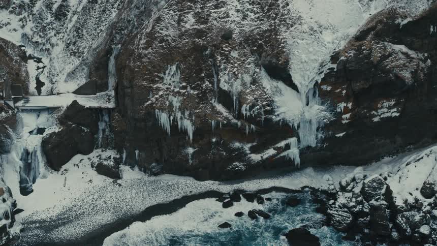The waves crash against the frozen shore