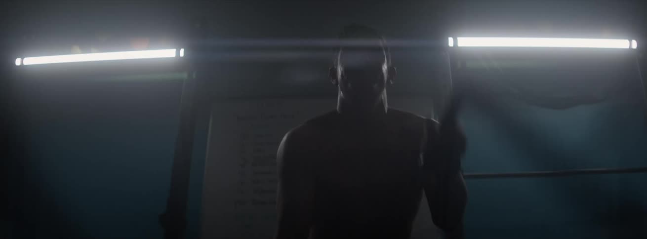 Man performing cardio in a lowlit gym as he slams ropes toward the floor