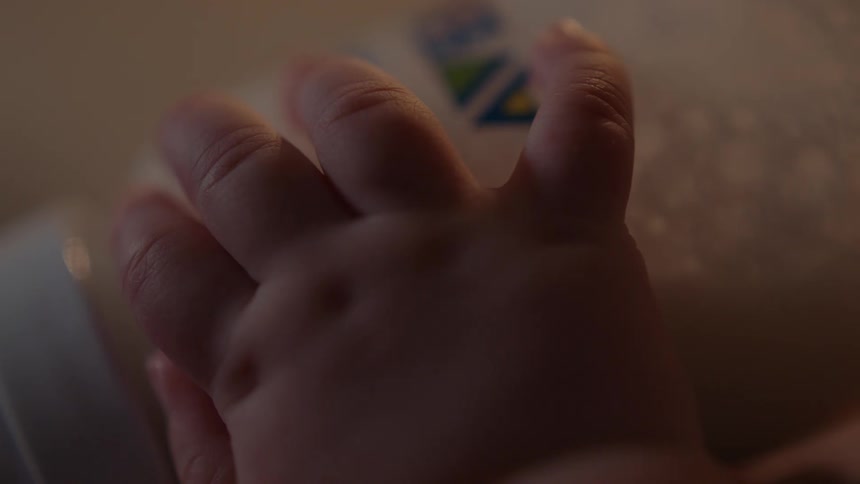 A babys hand holding a bottle of milk