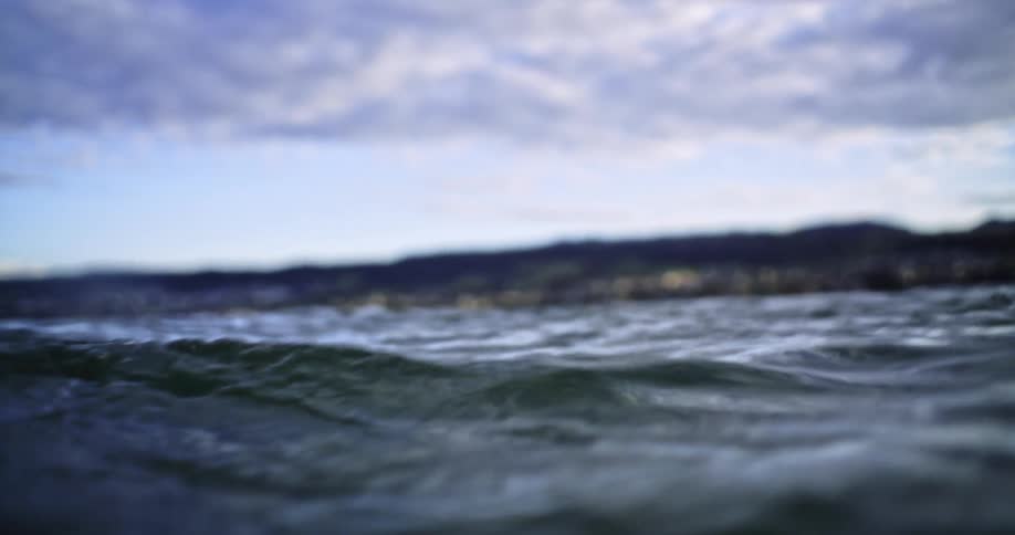 View from inside the sea with calm waves on a blue sky day with clouds