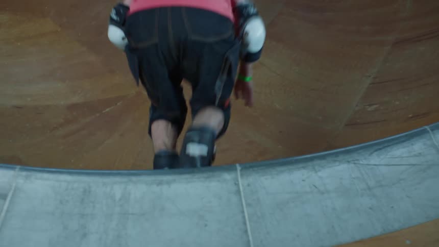 Back view of an elderly man crossing a wooden sling track with roller skates