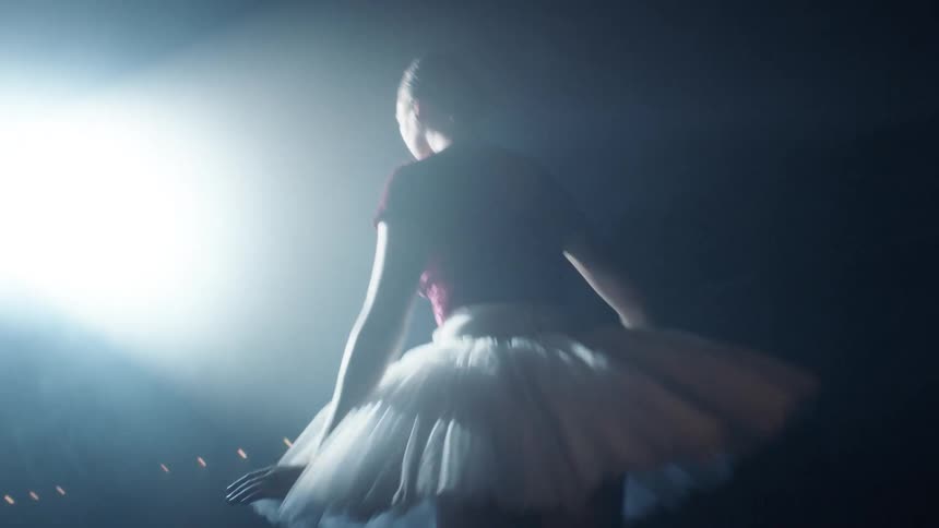 A ballerina pirouettes under a spotlight