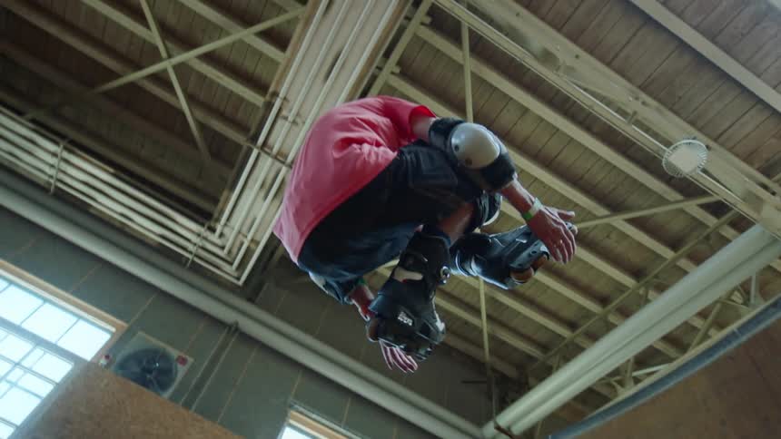 Legs of a person with roller skates doing a trick on a wooden track
