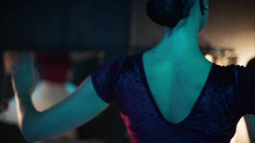 A ballerina practicing in front of a mirror in the dressing room