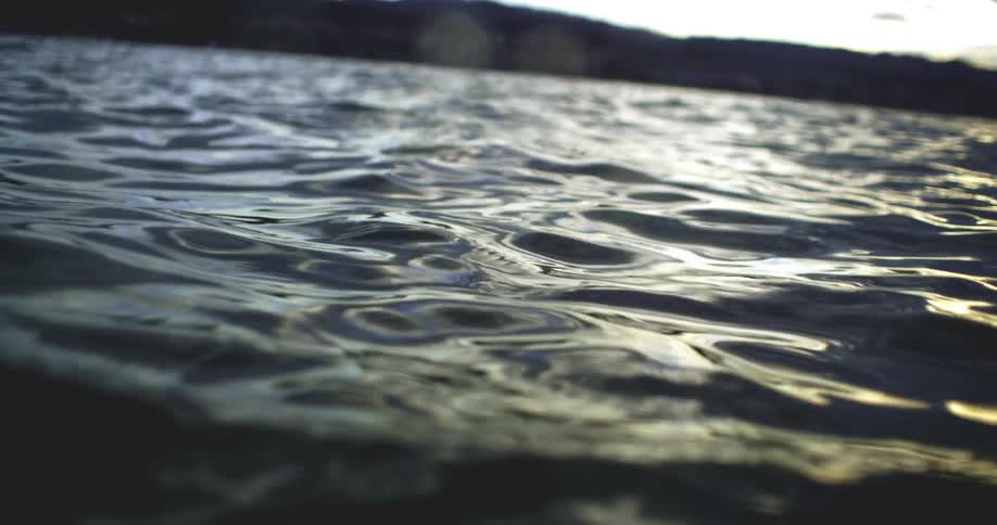 Closeup view of rippling water with hills in the background at sunset