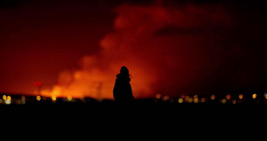 Volcano erupts in background as people walk in the city
