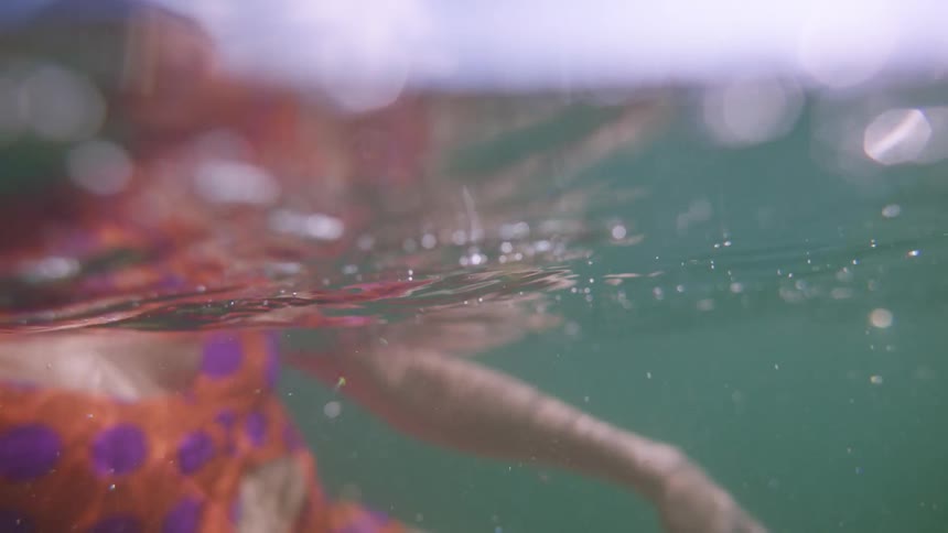 Woman swimming in a crystal clear sea a solar reflection