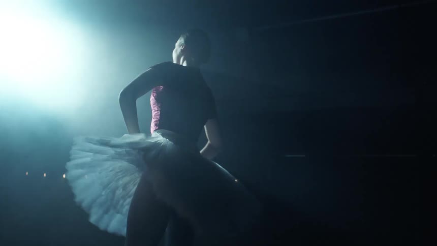 A ballerina dancing on stage under a spotlight