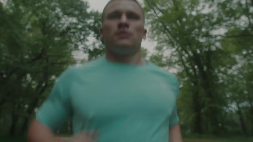 Portrait of a concentrated man running in a natural environment like trees vegetation around