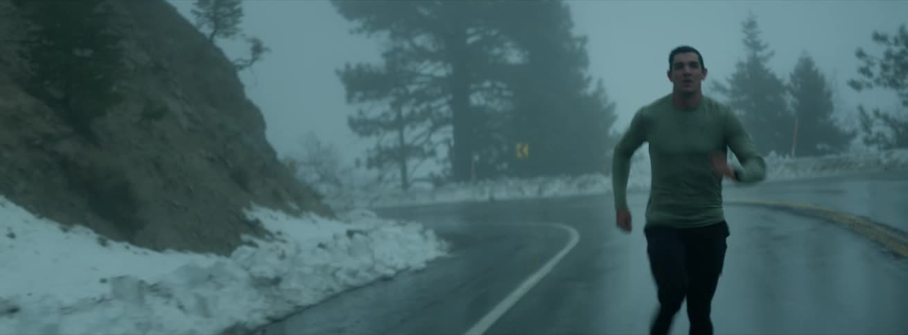 A man is running down the highway on a foggy day