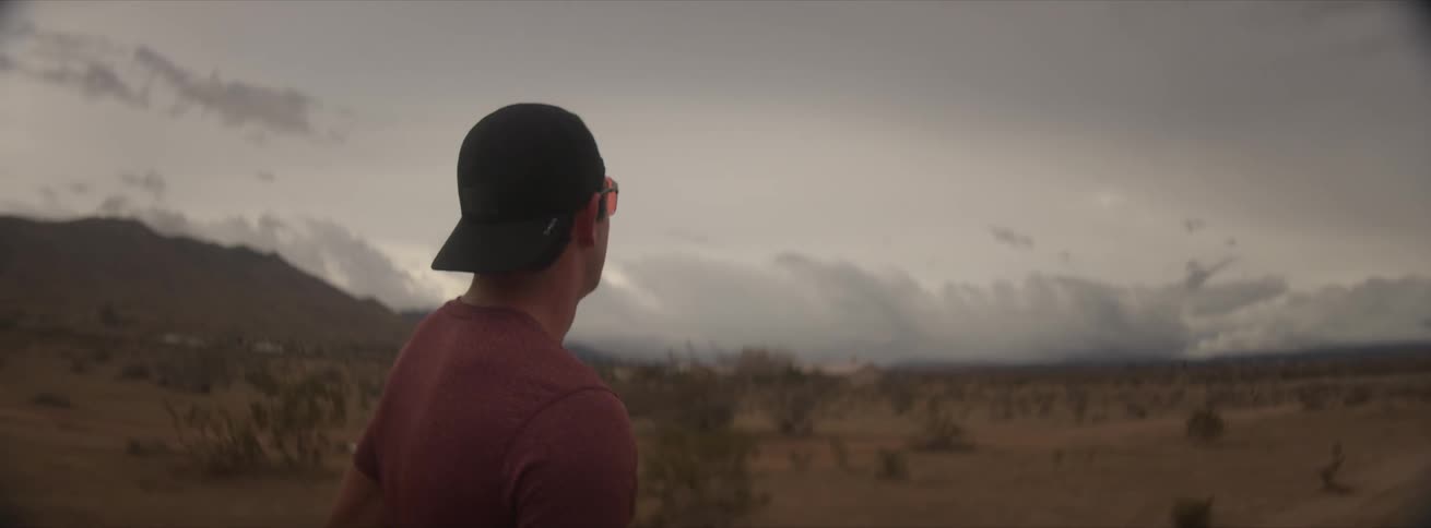Cyclist man enjoying the view in a desert location with mountains around on a cloudy day