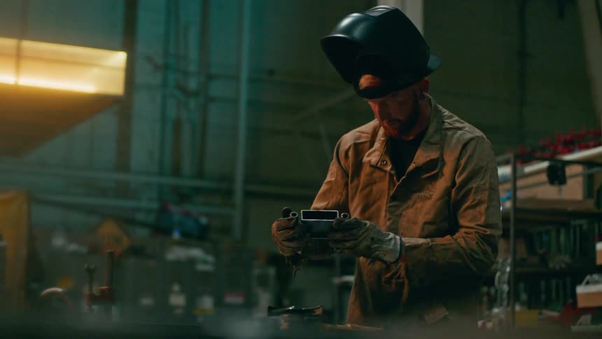 Welder man with gloves analyzing a metallic object