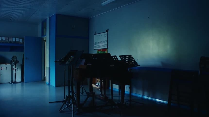 Dimly lit room with a piano and music stands