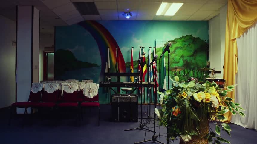 Room prepared for an event with a rainbow mural and international flags on stage