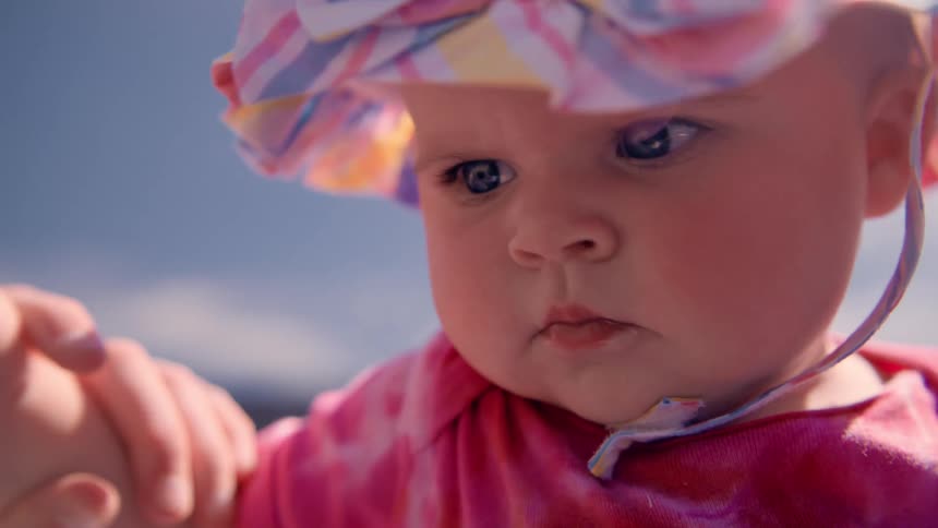 Close up of the face of a baby wearing colorful summer clothes outdoors