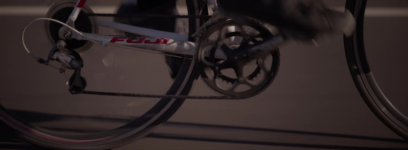Closeup of the legs of a cyclist pedaling at an intense speed on a road