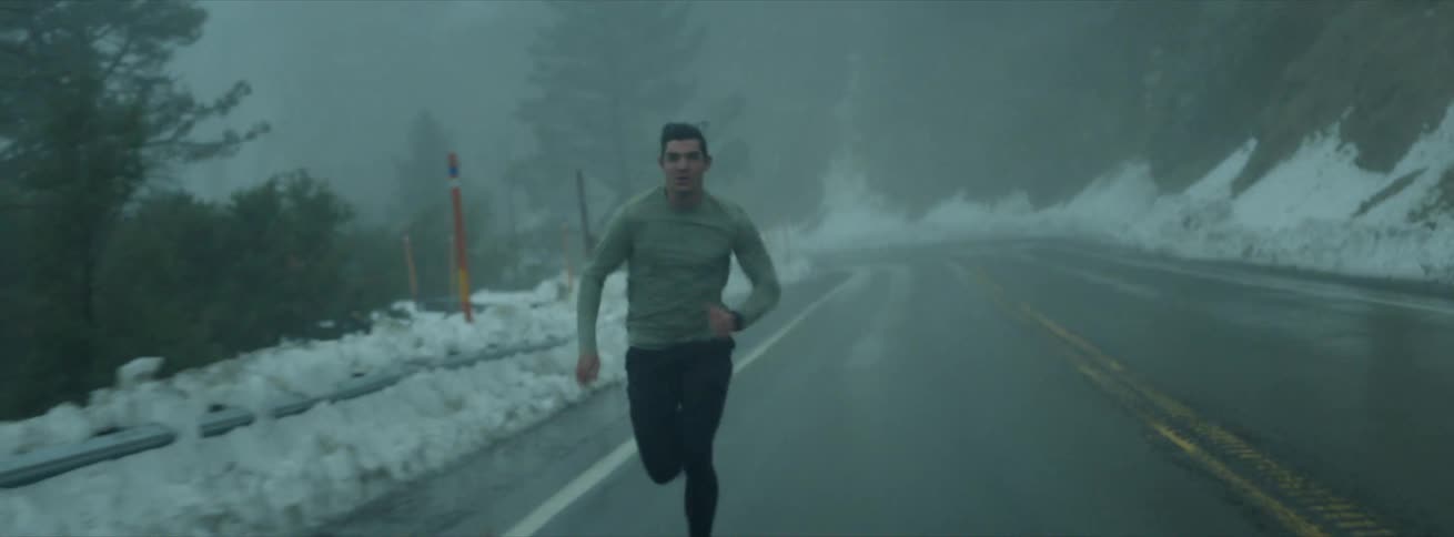 Man runs down the snowlined roads on a cloudy winter day