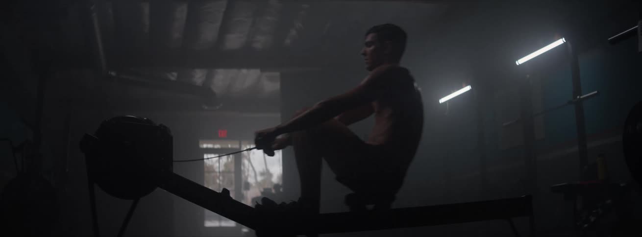 Silhouette of a man exercising on a dimly lit gym