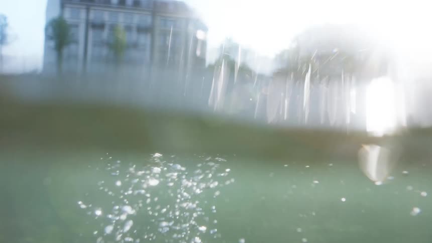 A female hand submerges in water creating air bubbles