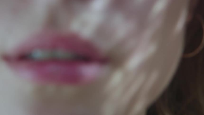 Closeup on a womans mouth with pink lipstick and the suns reflection on her face