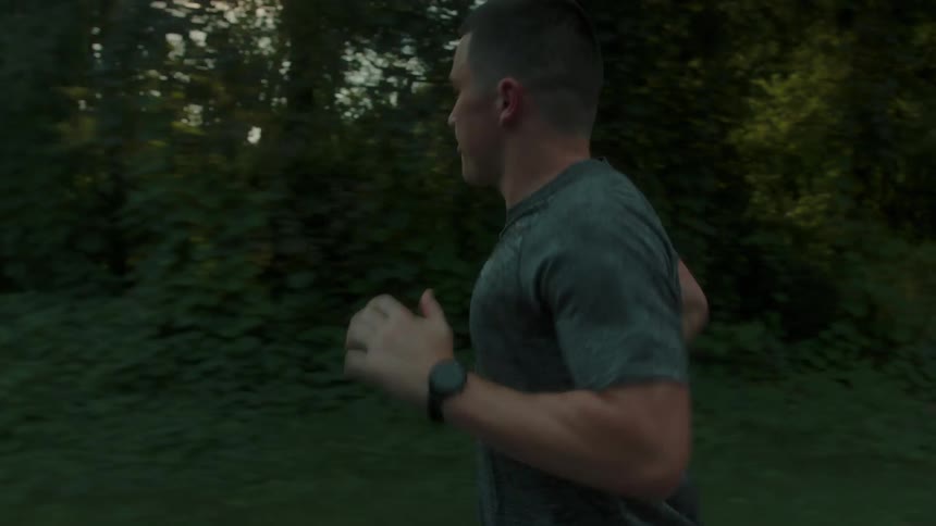 A muscular man moves quickly as he goes for a run outdoors