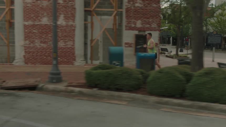 Man running on the city sidewalk in a straight line