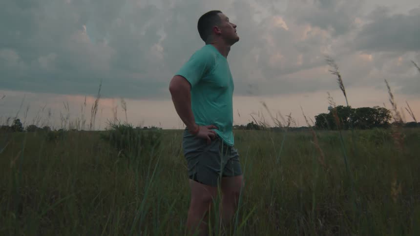 Man standing looking up while standing in a natural field on a sky tomorrow with clouds