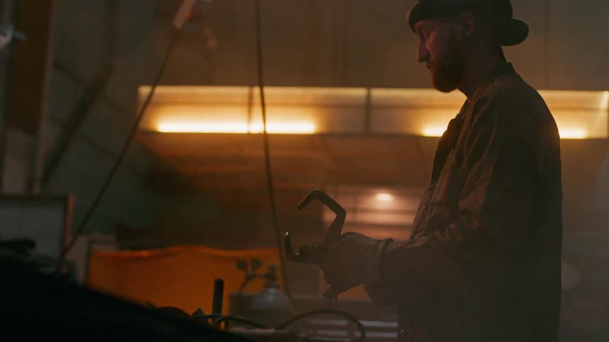 Welder man inside a factory holding a metal tool