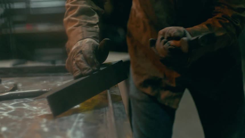 A worker hammers metal