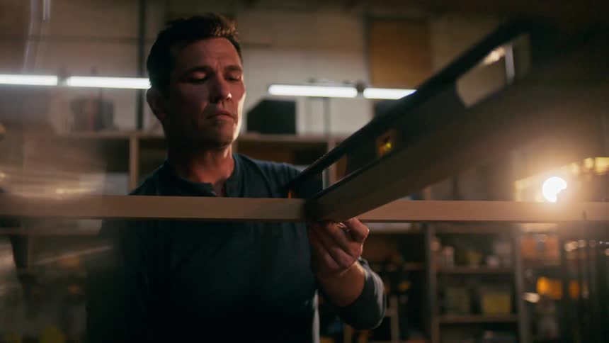 Concentrated man with a ruler measuring a wooden sheet with the help of levels