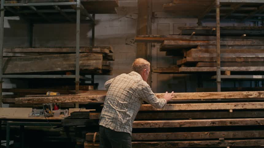 A man is examining lumber in a lumber yard