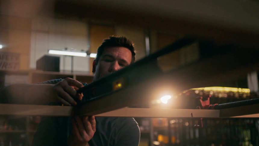 Carpenter checks for level at the joint between two slats of wood