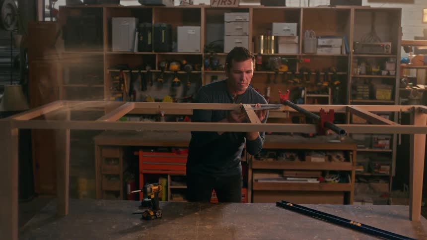A carpenter building a wooden frame in a workshop