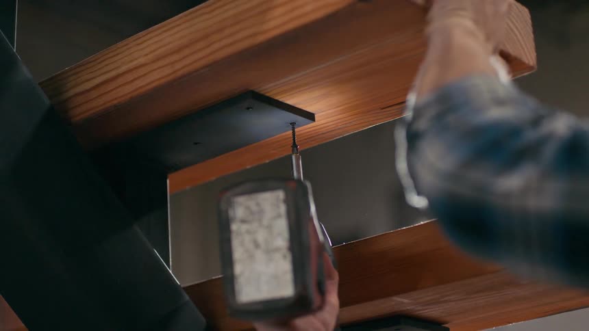 A man screws wood to a piece of metal