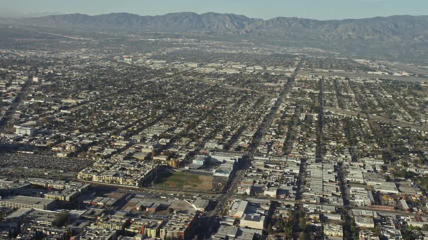 Aerial panorama of an urban city surrounded by mountains on a cloudless blue sky day