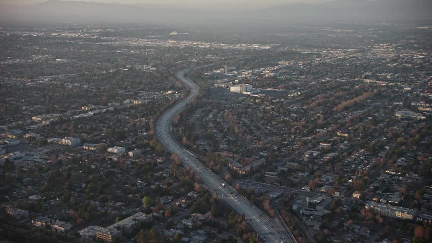 Aerial panorama of a long highway in an urban city with the silhouette of mountains on the horizon