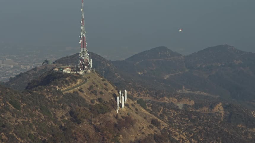 Aerial stock footage of a helicopter flying next to a tower over hollywood hills