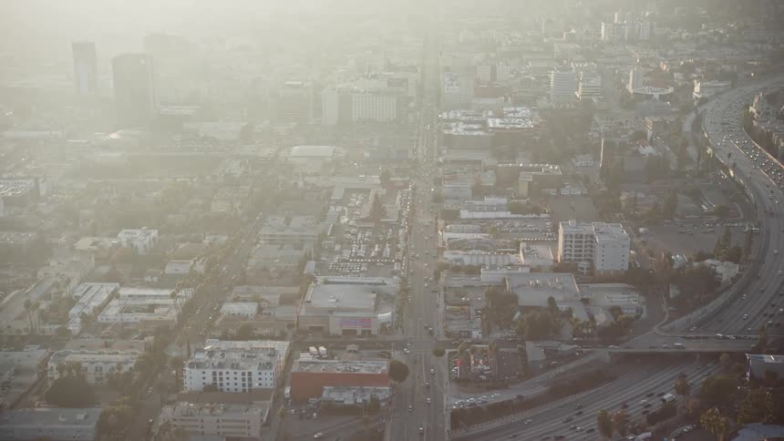Aerial view of a city at dusk with illuminated buildings and a busy highway