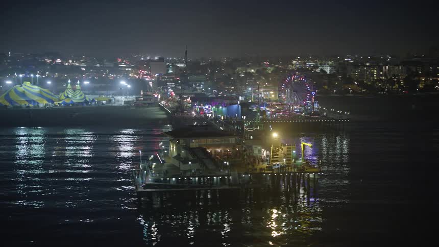 Aerial panorama of a park at night on a dock in the sea on the edge of a metropolis
