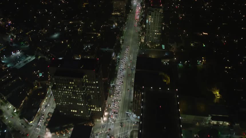 A nighttime aerial view of a city with illuminated streets and buildings