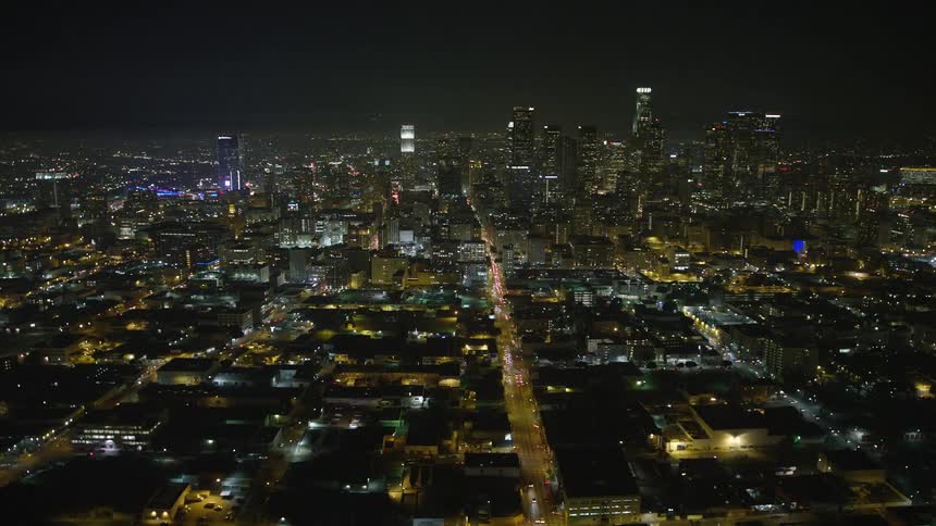 Aerial panorama of a city with skyscrapers and residential neighborhoods illuminated at night