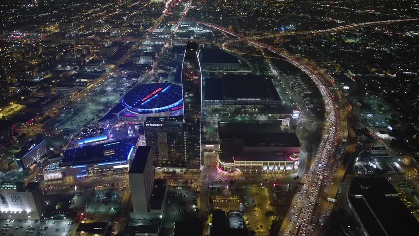 Aerial panorama of a metropolis with modern buildings and a stadium illuminated at night